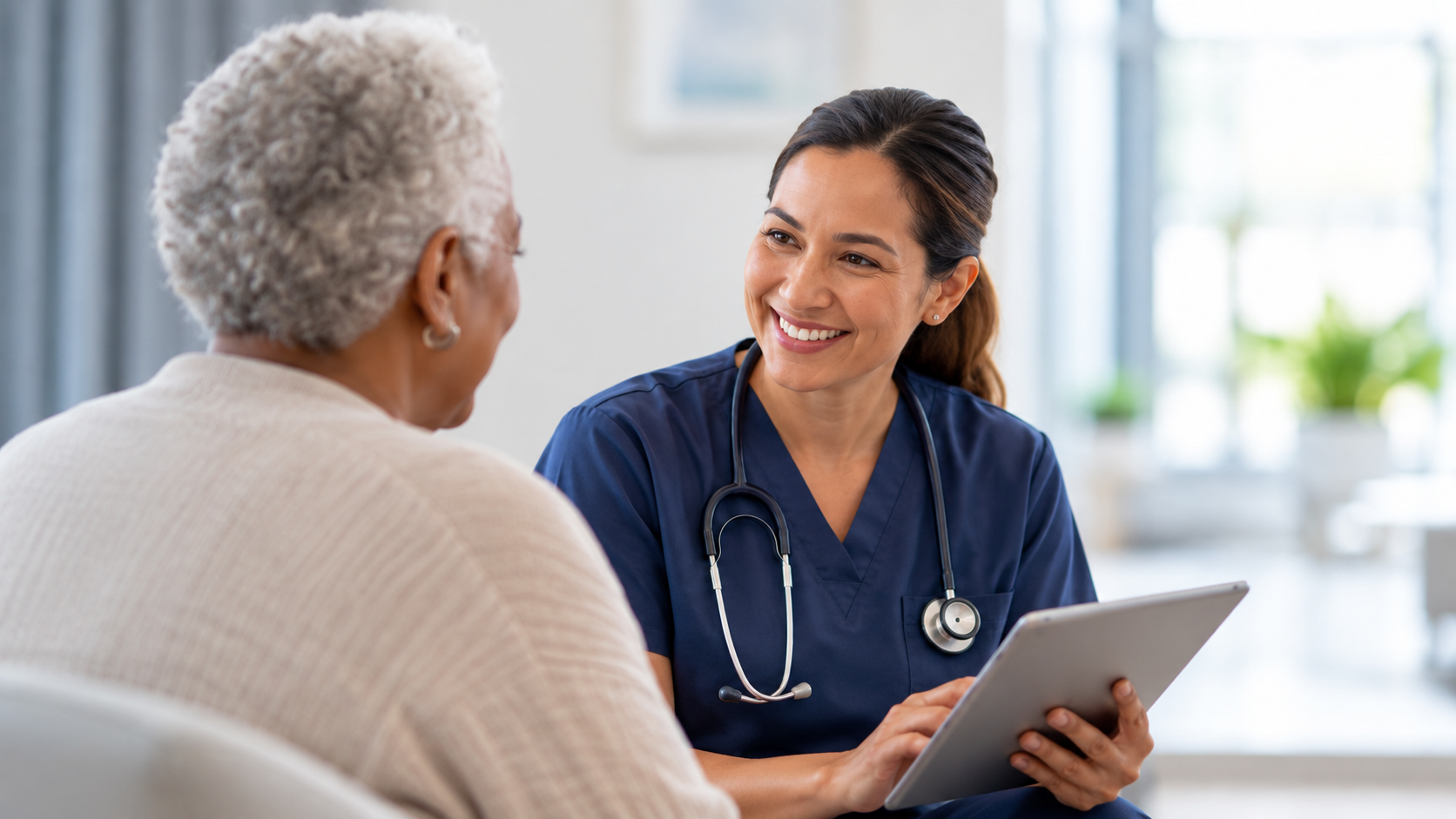 Healthcare professional speaking with an older patient while holding a tablet